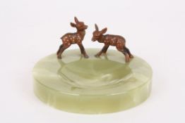 A 1930s onyx and cold painted pin traymounted with a pair of cold painted spelter fawns, on a