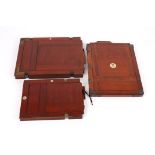 A collection of three early 20th century mahogany camera plates
each with inset numbers, the