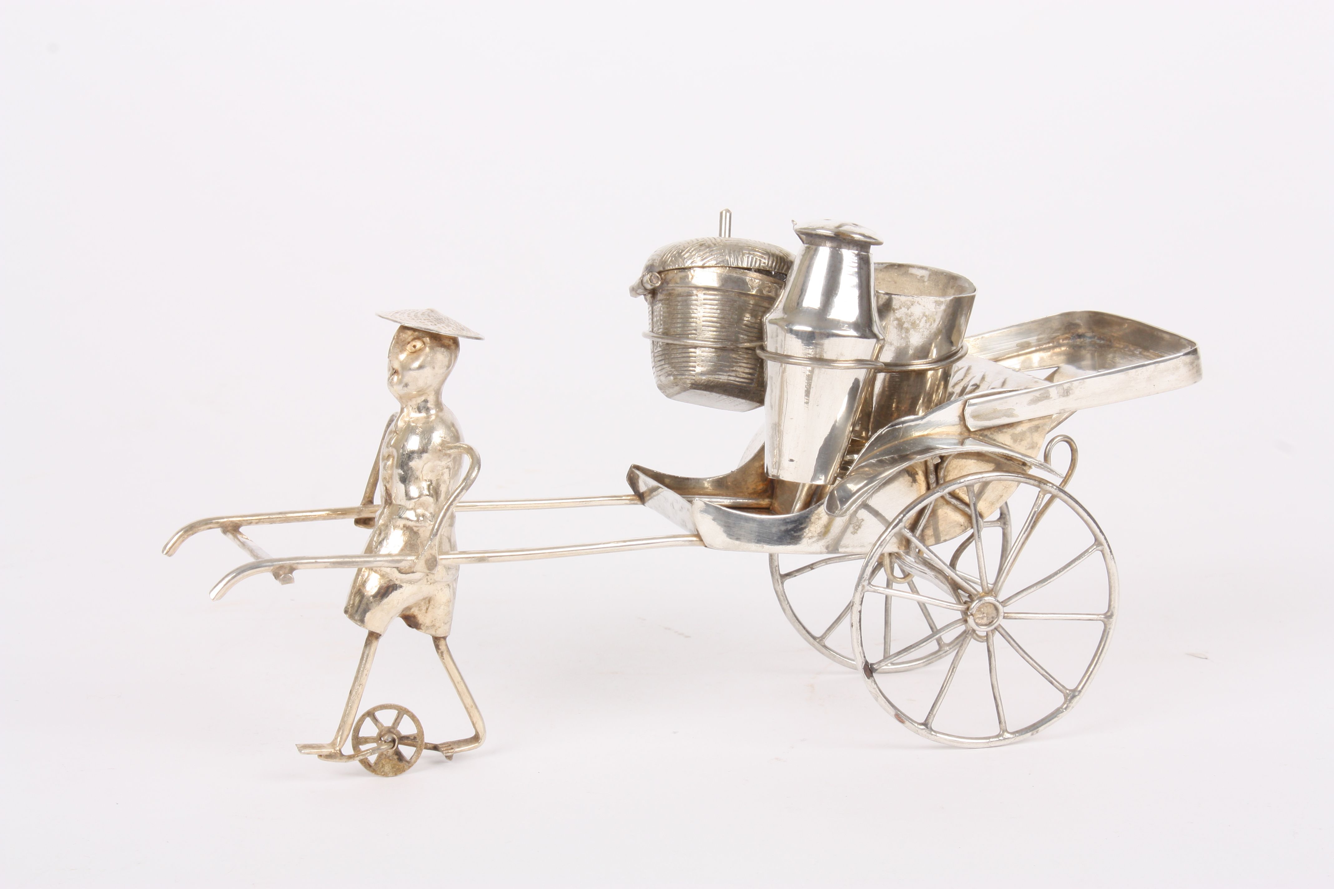 An early 20th century Chinese white metal novelty cruet set
in the form of a Rickshaw, being