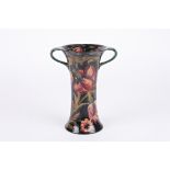 A William Moorcroft tubelined trumpet vase
with twin handles, decorated with red flowers and