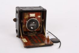 An early 20th century mahogany and red bellows Sanderson plate camerawith black covered body,