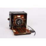 An early 20th century mahogany and red bellows Sanderson plate camera
with black covered body,