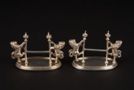 A pair of early 20th century Mappin & Webb silver plated knife restsformed as rampant lions holding