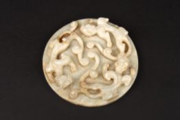 A large 20th century Chinese carved pale jade roundel carved in high relief with three water