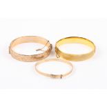 Two 9ct gold metal core stiff bangles
with engine turned decoration, together with a 9ct rolled gold