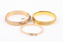 Two 9ct gold metal core stiff bangleswith engine turned decoration, together with a 9ct rolled gold