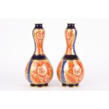 A pair of Macintyre double gourd vases
decorated with red flowers on blue and gilt grounds, the base