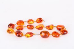 A set of amber coloured beadsabstract shaped with inclusions, together with a few spare beads,