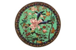 A cloisonné enamel chargerdecorated with birds in flight amidst flowers and foliage against a green