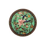 A cloisonné enamel charger
decorated with birds in flight amidst flowers and foliage against a green