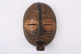 An early 20th century African tribal carved wooden maskwith stylised slitted eyes, the whole face