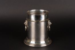 A silver plated wine bottle holderwith twin lions head ring handles and supported on a circular