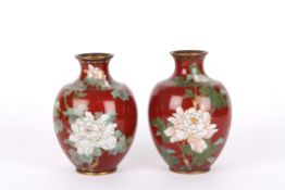 A pair of brass and enamel vasesof bulbous form, with blossoming flowers and butterflies on a red