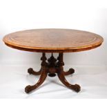 A Victorian figured walnut oval loo table
the inlaid top with tilting action and supported on turned