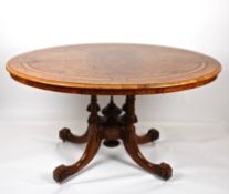 A Victorian figured walnut oval loo tablethe inlaid top with tilting action and supported on turned