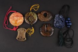 Six various 20th century Chinese carved hardstone pendants including a hollowed and pierced roundel,