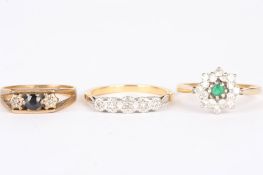 A group of three diamond ringscomprising an emerald and diamond daisy cluster ring set in 18ct