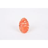 A Chinese carved coral and gold ring
set with a carved coral plaque of flowers, mounted in an