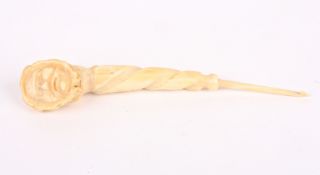 An unusual whale ivory crochet hookwith carved Eskimo head with fur hood, with twisted handle,