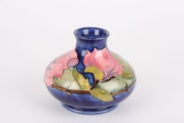 A Moorcroft Magnolia tubelined bottle vasedecorated with pink flowers on a blue ground, signed in