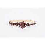 A Victorian Bohemian cut garnet hinged bangle with central floral cluster between arrow point