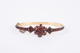 A Victorian Bohemian cut garnet hinged bangle with central floral cluster between arrow point