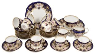 A Royal Crown Derby tea set decorated with vignettes of flowers on a rich blue, white and gilt