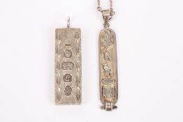 A hallmarked silver ounce ingot pendant and another silver pendant of Egyptian design decorated with