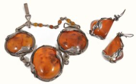 A contemporary honey amber bracelet having three large polished amber ovals set within white metal