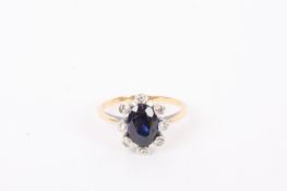 An sapphire and diamond point cluster ring, the central oval blue sapphire surrounded by collett