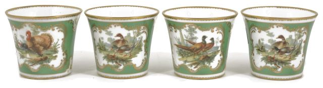 A set of four German porcelain beakers of flared form and painted with scenes of birds on a green