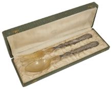 A pair of silver plated salad servers, and a set of cake servers both in fitted cases, the cake