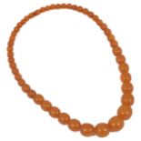 A set of graduated amber coloured beads with screw clasp 20mm to 8mm diameter. 58.5 cm long.