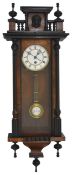 A Victorian walnut Vienna wall clock with white enamel dial and black Roman numerals, within a