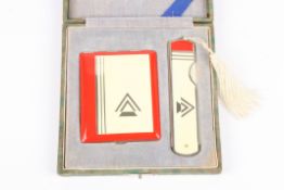 An Art Deco cased compact and folding comb decorated with an arrow design in cream and red, in a