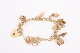 A 9ct gold open curb link charm bracelet with heart padlock fastening, gold charms include a