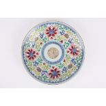 A Chinese famille rose plate decorated with a central roundel, surrounded by enamel flowers, with