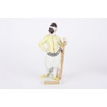 A 20th century Meissen porcelain figure of a harlequin stood holding a paddle and wearing a face