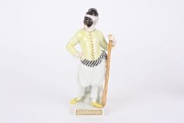 A 20th century Meissen porcelain figure of a harlequin stood holding a paddle and wearing a face