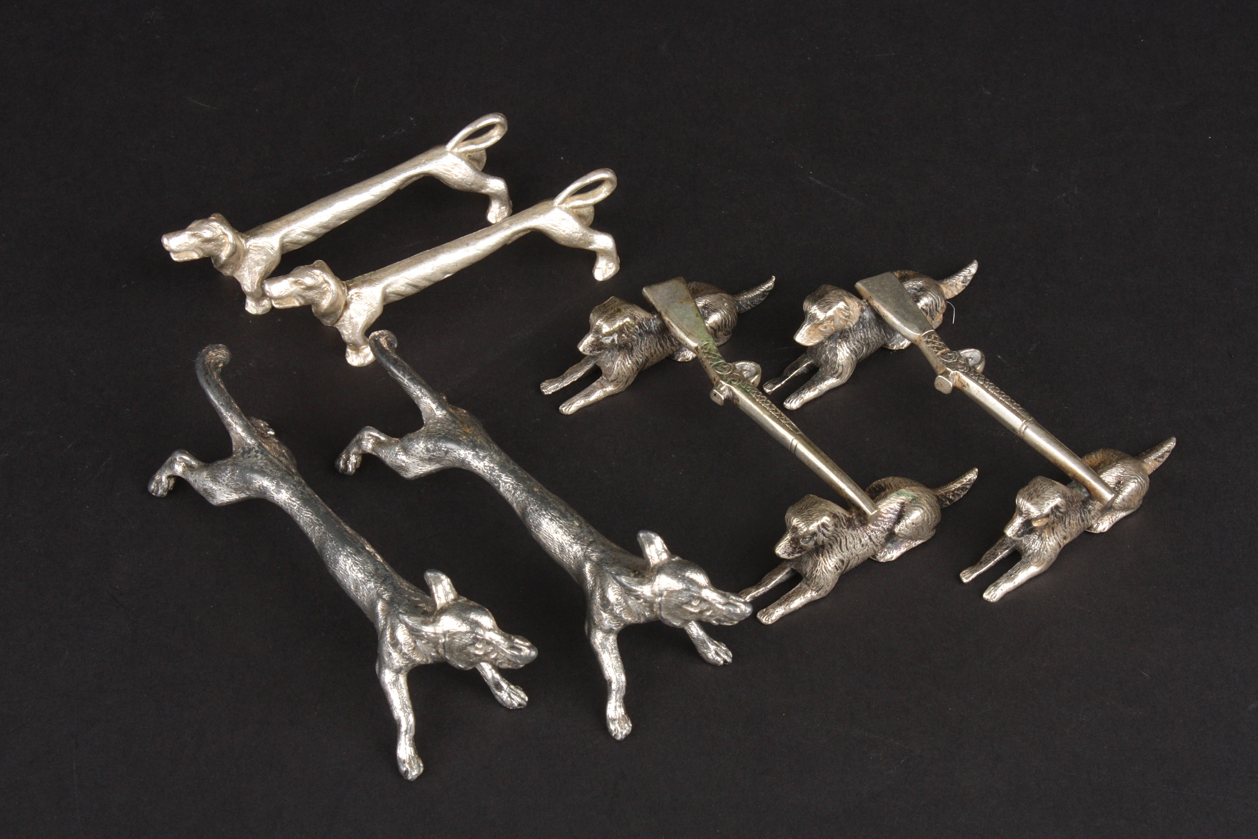 Three pairs of silver plated dog knife rests one with bar in the form of hunting guns Condition: