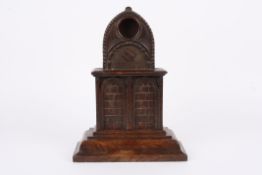 A large Victorian carved oak pocket watch stand of architectural form with arched top and pocket