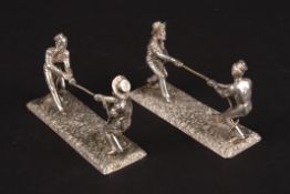 An unusual pair of Victorian silver plated knife rests depicting men playing tug of war, supported