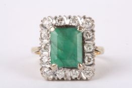 A large emerald and diamond set rectangular cluster ring the central emerald set within a border