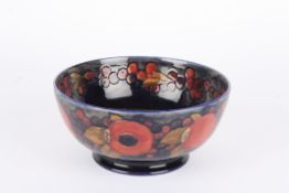 A Moorcroft Pomegranate bowl with tubelined decoration on a blue ground with impressed mark to