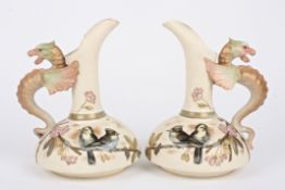 A pair of late 19th century Continental porcelain ewers painted with birds and flowers on an ivory