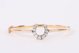 A Victorian diamond set horseshoe bangle, the yellow metal, hinged bangle incorporating a