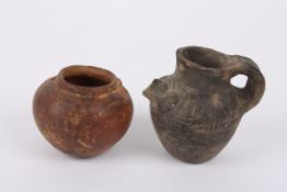 Two pieces of Pre-Colombian pottery comprising a hanging oil pot, and a jug decorated with a