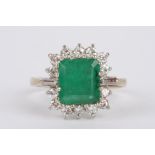 A Continental rectangular emerald and diamond set cluster ring the central step cut emerald