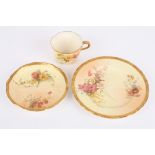 A Royal Worcester blush ivory cup, saucer and plate trio, decorated with flowers, puce mark to the