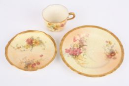 A Royal Worcester blush ivory cup, saucer and plate trio, decorated with flowers, puce mark to the